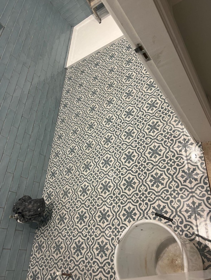 Blue metro wall tiles and patterned floor tiles during tiling